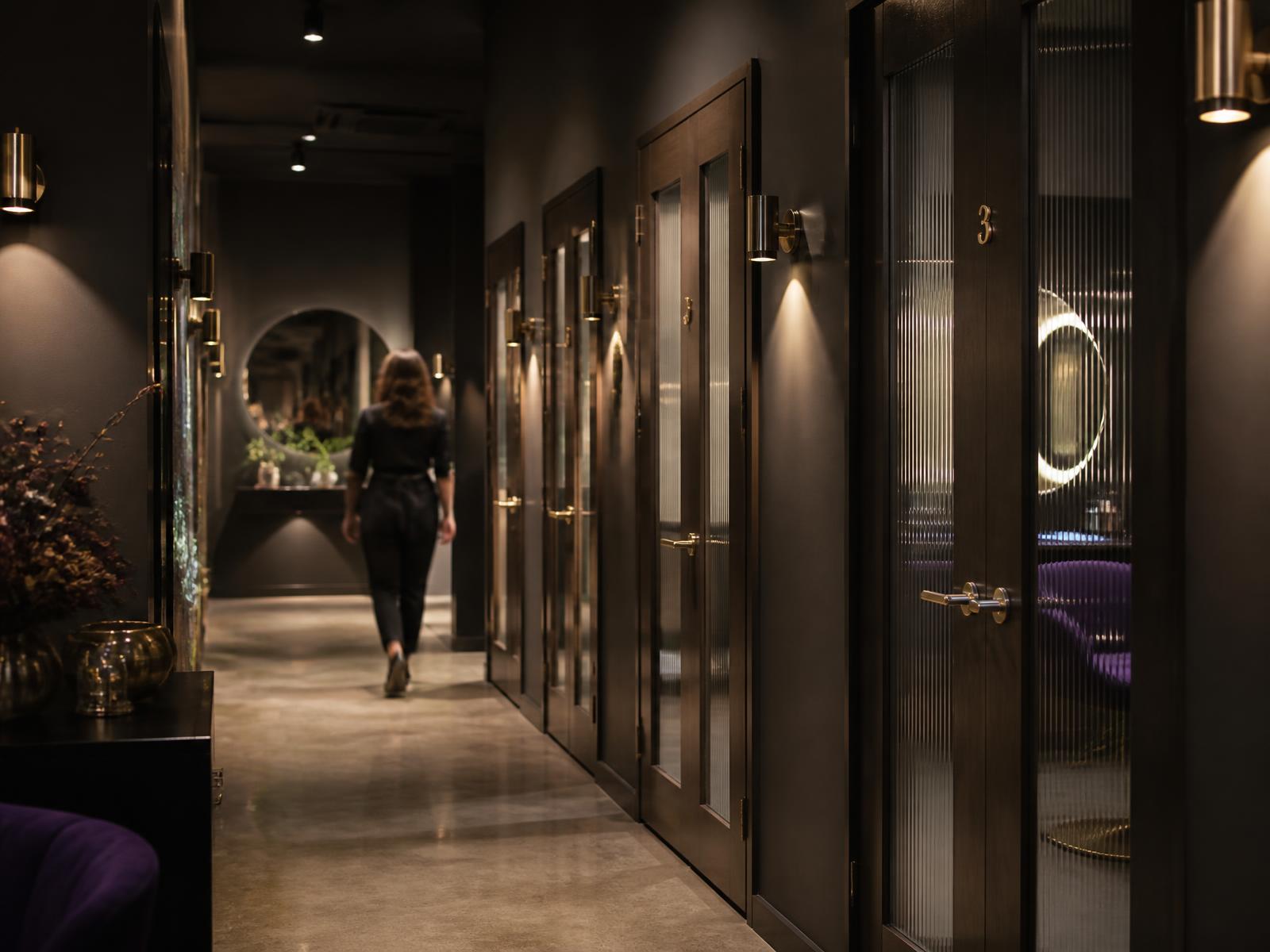 Private salon suite corridor with individual studio doors and warm accent lighting